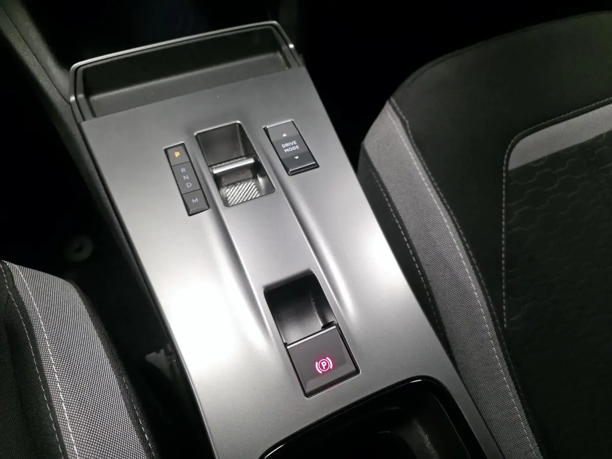 Vue rapprochée de la console centrale grise avec sélecteur de boîte automatique et frein à main électrique dans un Opel Mokka noir.