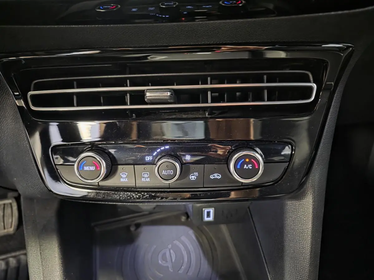Détail de la console centrale noire de l’Opel Mokka 2025 avec commandes climatisation et recharge smartphone sans fil.