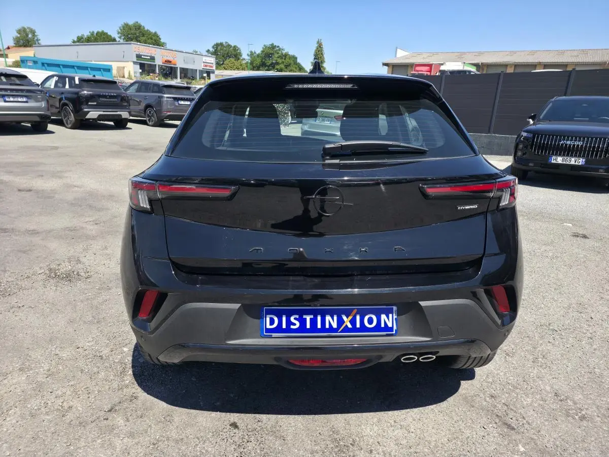 Vue arrière d'un Opel Mokka noir 2025 avec double sortie d'échappement et logo "Hybrid" à droite.