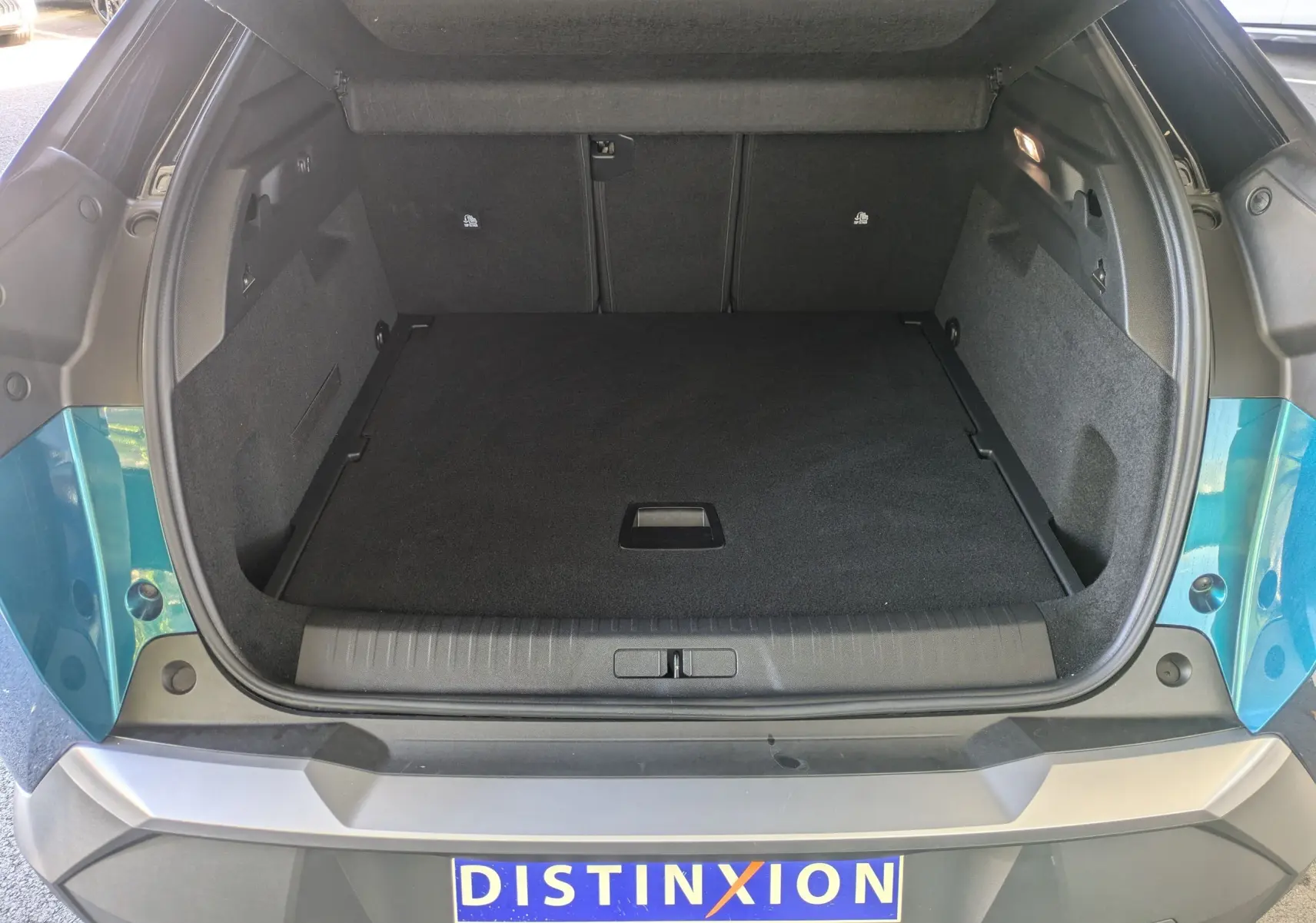 Coffre ouvert vu de l'arrière d'un Peugeot 3008 Hybrid 145 GT bleu Obsession avec toit noir, intérieur noir.