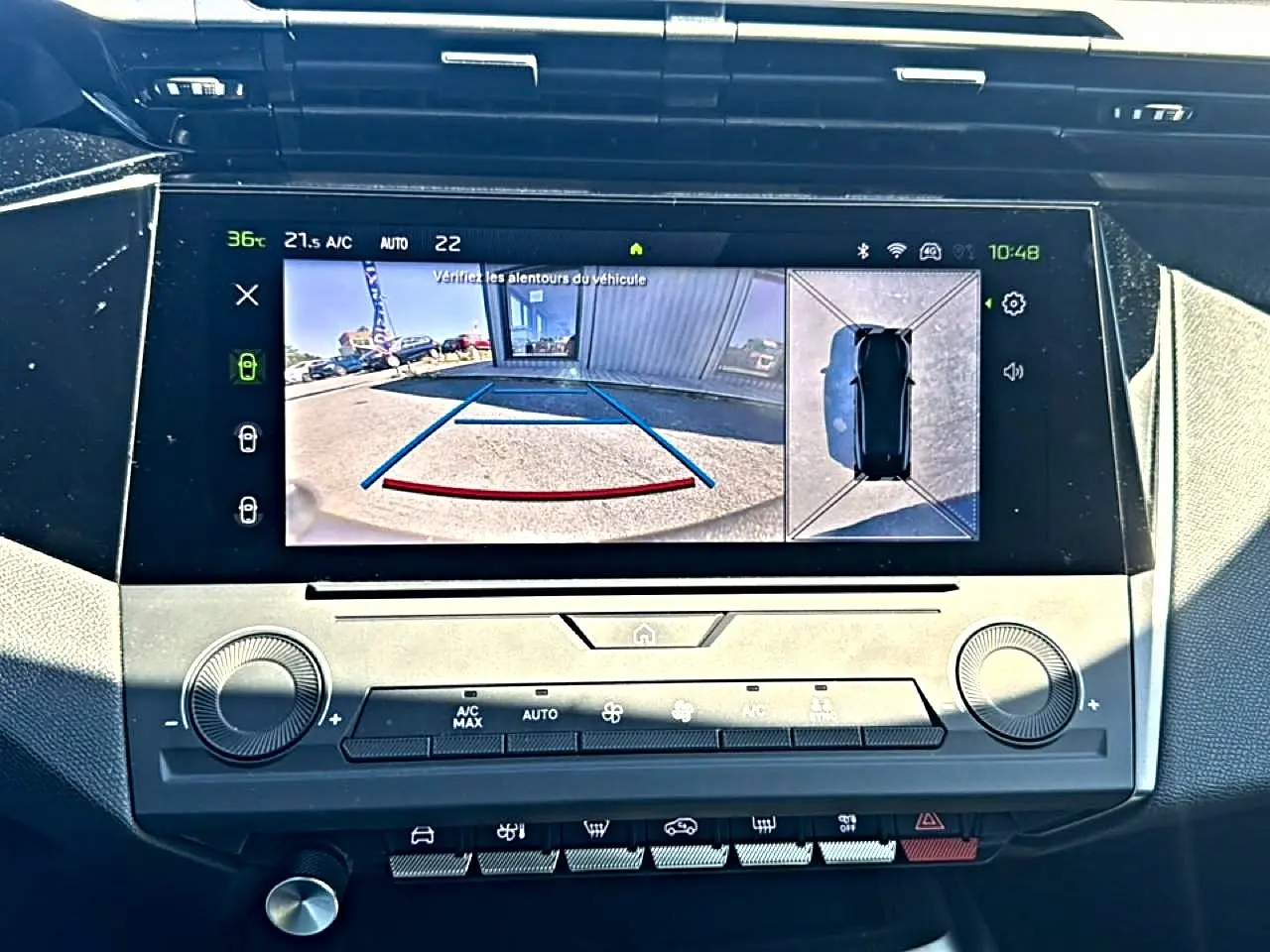 Écran tactile central de la Peugeot 408 Hybrid 145 allure noir montrant la caméra de recul et vue à 360° du véhicule.