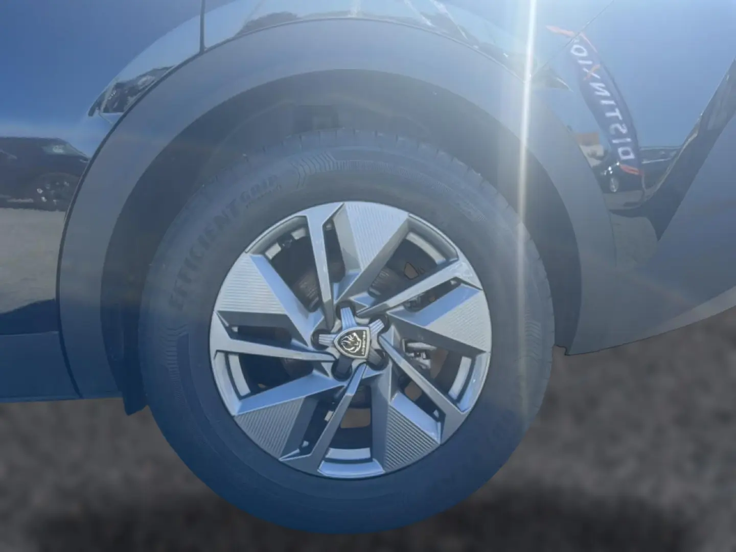 Gros plan sur la jante alu avant droite noire du Peugeot 408 Hybrid 145 allure e-dcs6 avec logo central Peugeot.