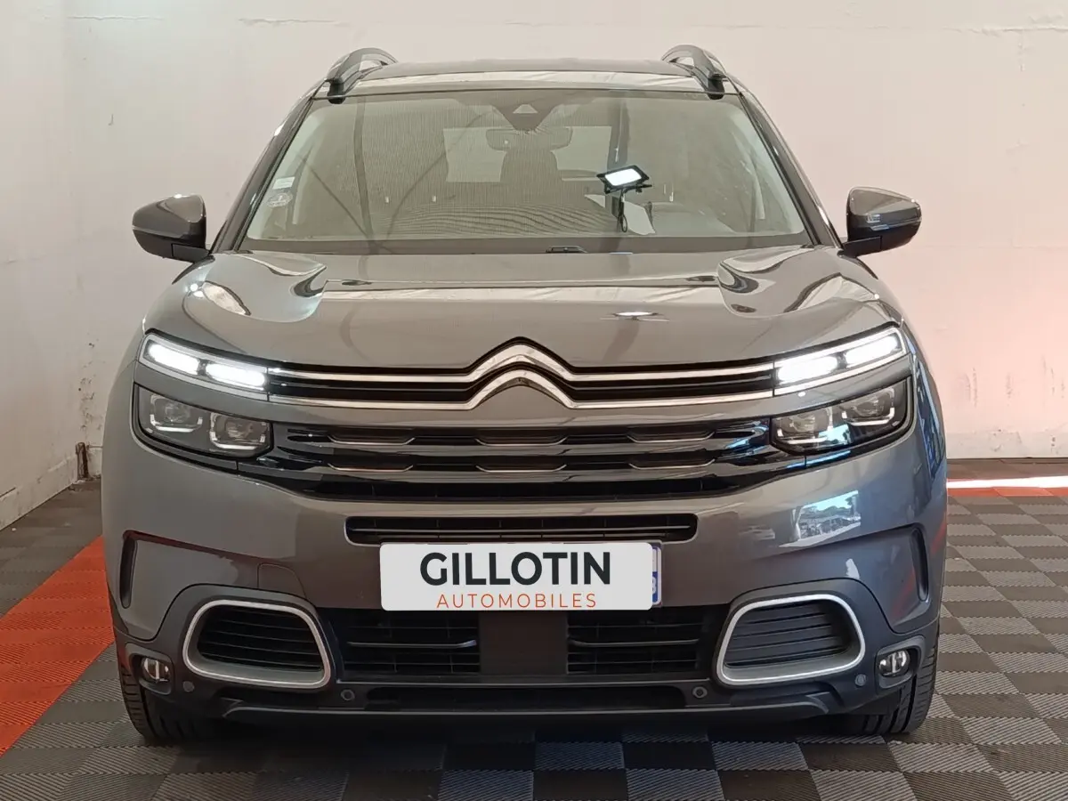 Vue frontale d'un Citroën C5 Aircross Hybrid gris foncé avec feux LED allumés et calandre distinctive.