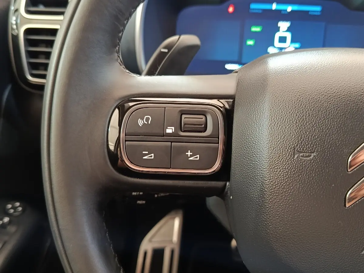 Gros plan sur les commandes gauche du volant cuir noir du Citroën C5 Aircross Hybrid 225 ë-EAT8 Shine Pack 2021.