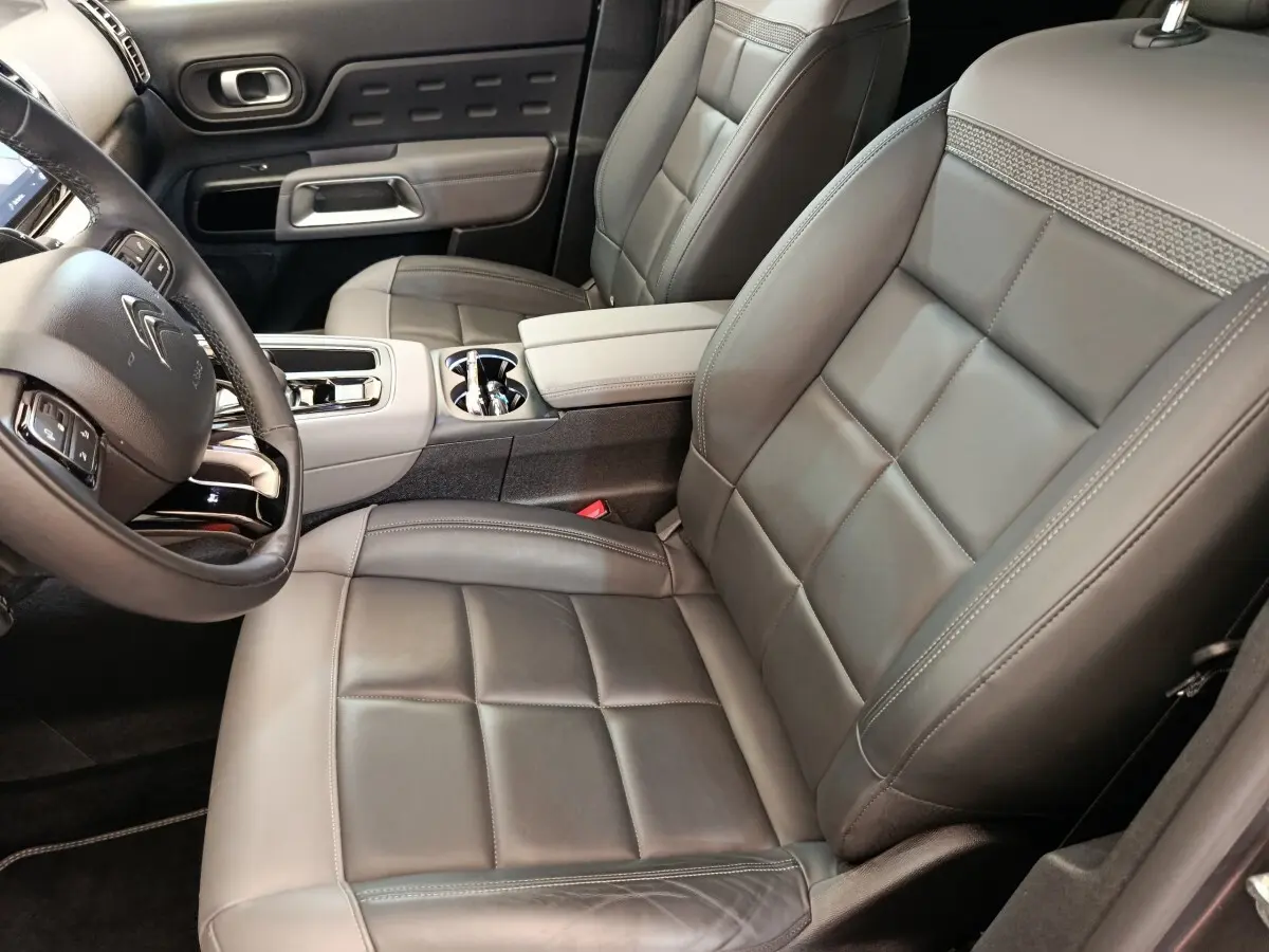 Vue intérieure côté conducteur du Citroën C5 Aircross Hybrid 225 avec sièges cuir gris et console centrale élégante.
