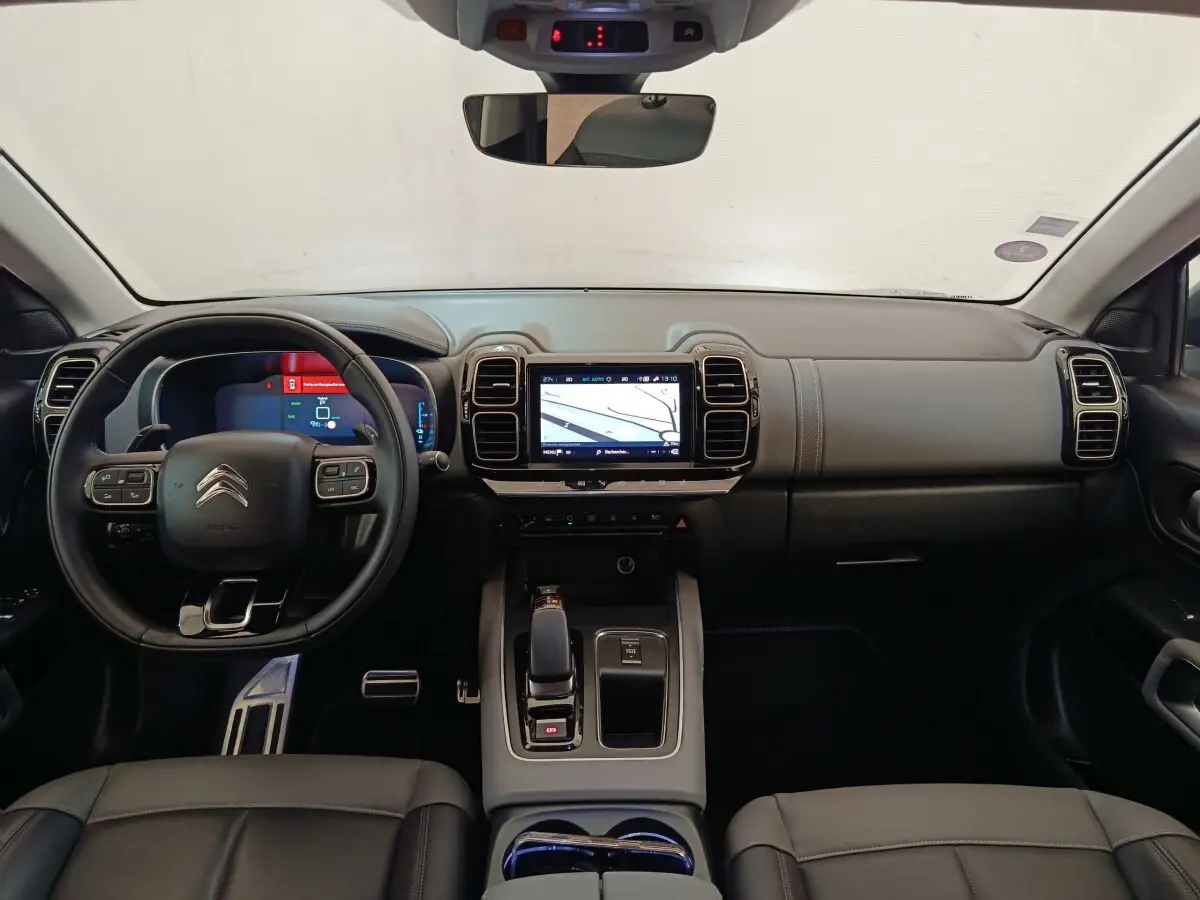 Vue intérieure frontale du tableau de bord et volant cuir noir du Citroën C5 Aircross Hybrid 225 ë-EAT8 Shine Pack.