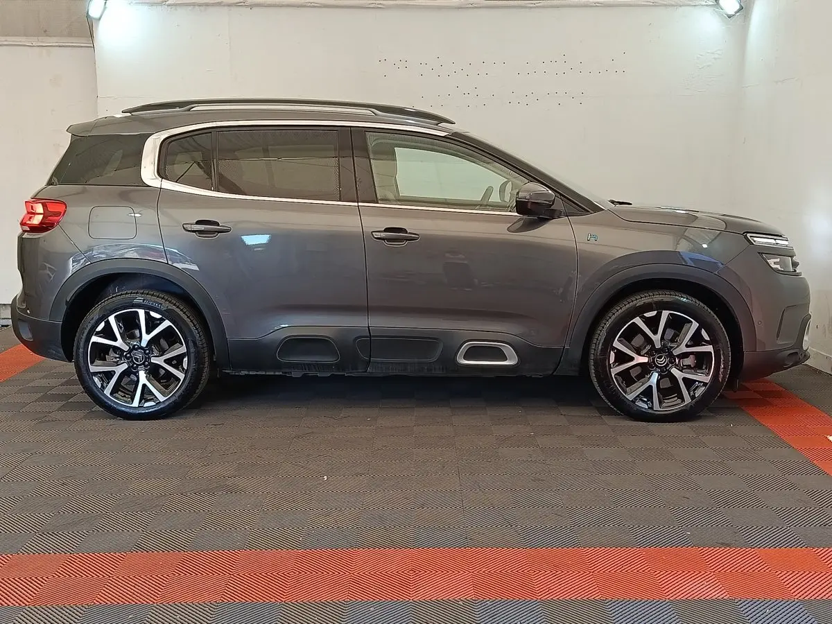 Profil droit du Citroën C5 Aircross Hybrid gris foncé avec jantes alliage et barres de toit chromées.