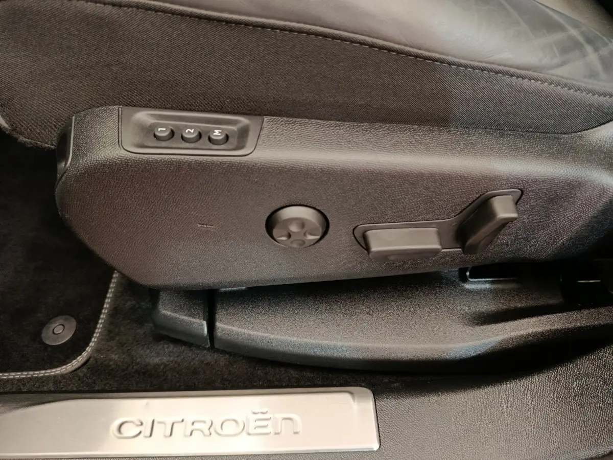 Détail des commandes de réglage du siège côté conducteur d’un Citroën C5 Aircross Hybrid 225 ë-EAT8 Shine Pack gris foncé.