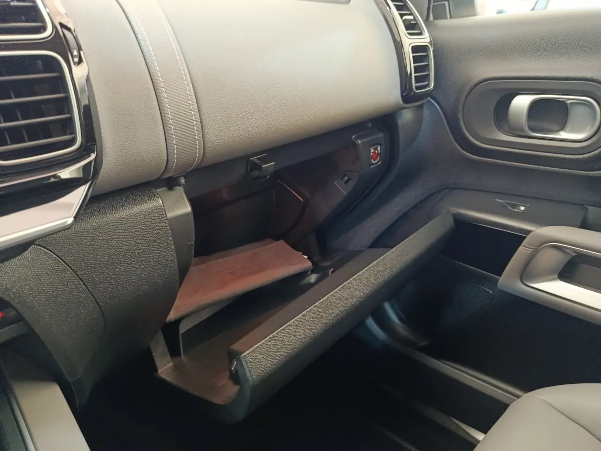 Intérieur côté passager du Citroën C5 Aircross Hybrid 225, boîte à gants ouverte avec finition cuir gris et plastique noir.