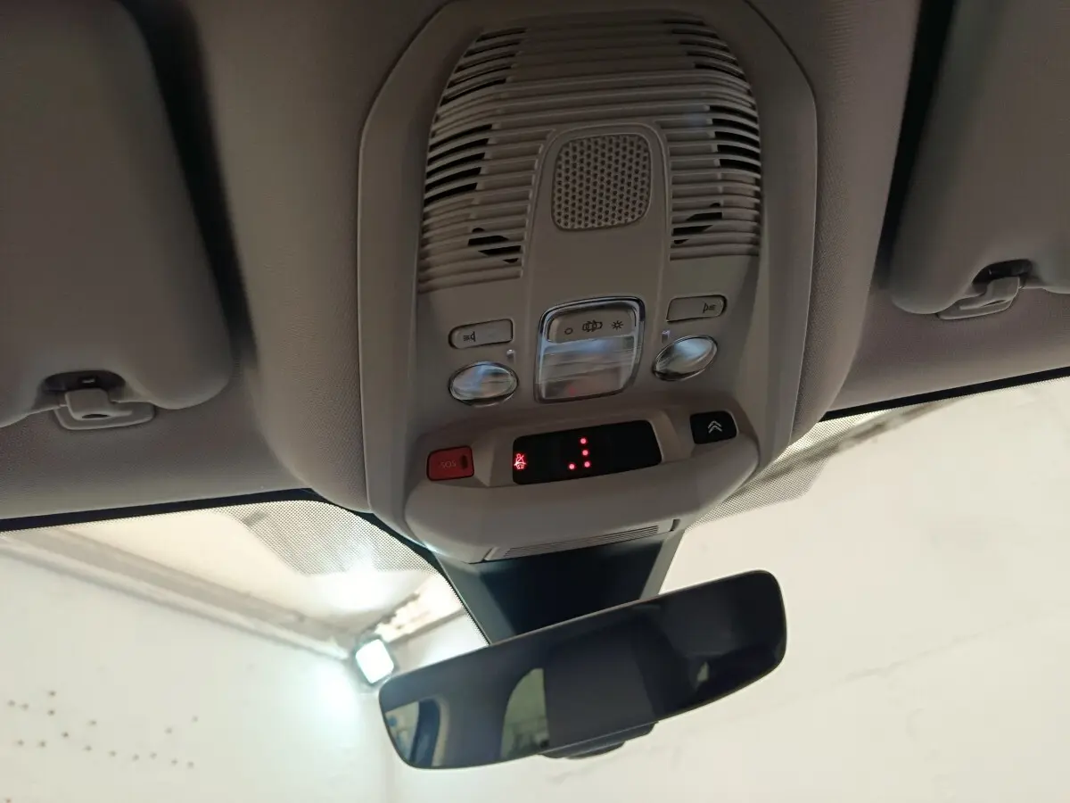 Vue intérieure du plafonnier gris clair avec commandes d’éclairage et rétroviseur intérieur d’un Citroën C5 Aircross Hybrid 225 Shine Pack.