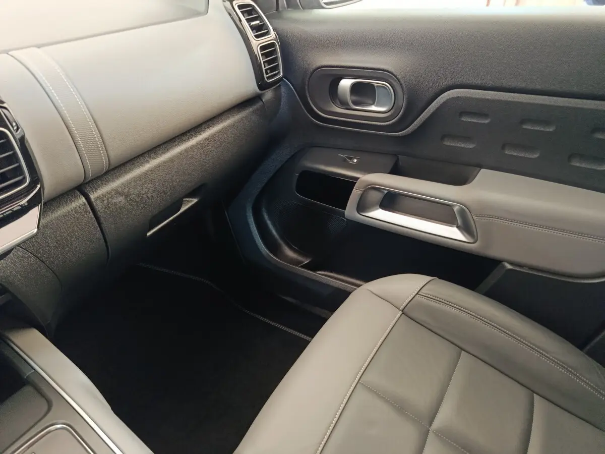 Intérieur gris clair du passager avant du Citroën C5 Aircross Hybrid, avec tableau de bord et porte au design moderne.