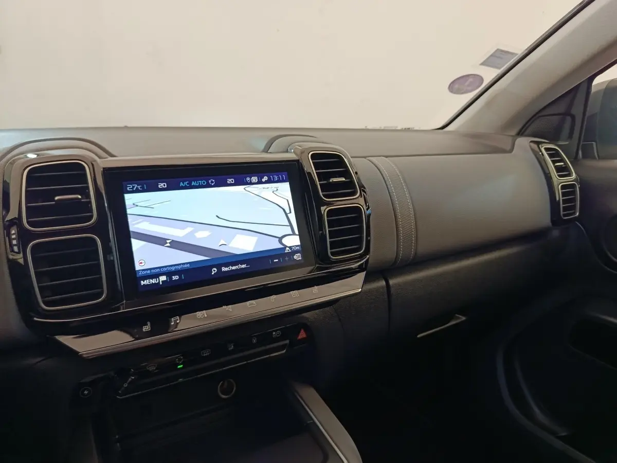Vue intérieure côté passager du tableau de bord gris foncé du Citroën C5 Aircross Hybrid avec écran tactile de navigation allumé.