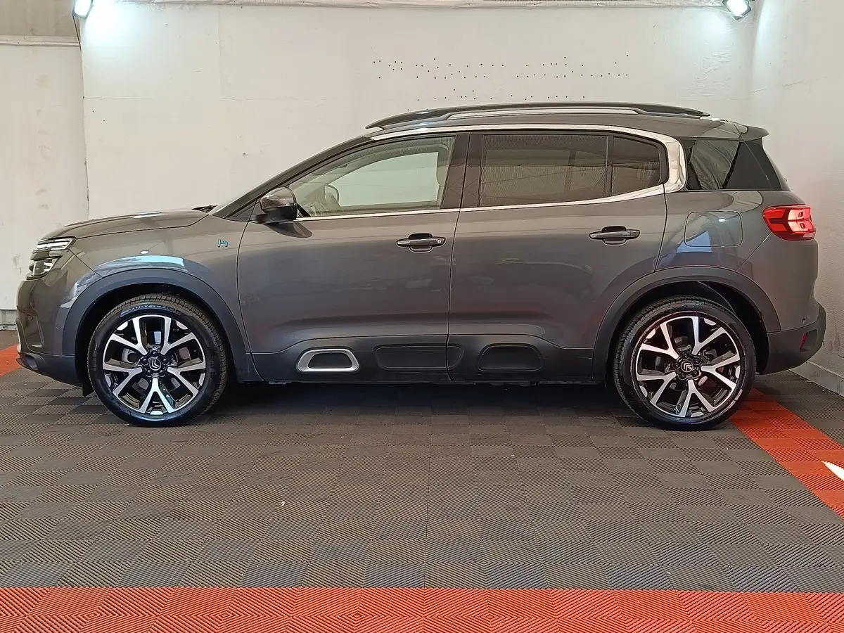 Profil droit d'un Citroën C5 Aircross Hybrid gris foncé avec jantes alliage et barres de toit chromées.