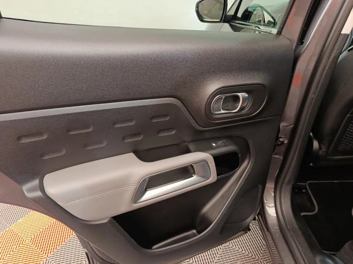 Vue rapprochée de la porte arrière droite gris foncé du Citroën C5 Aircross Hybrid avec accoudoir clair et poignée intégrée.