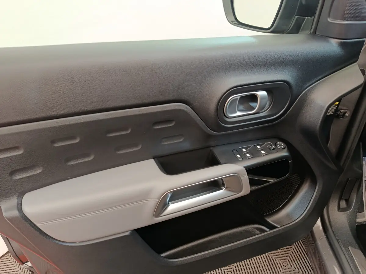 Intérieur côté conducteur de Citroën C5 Aircross Hybrid 225 ë-EAT8 Shine Pack, porte noire avec accoudoir gris clair et commandes électriques.
