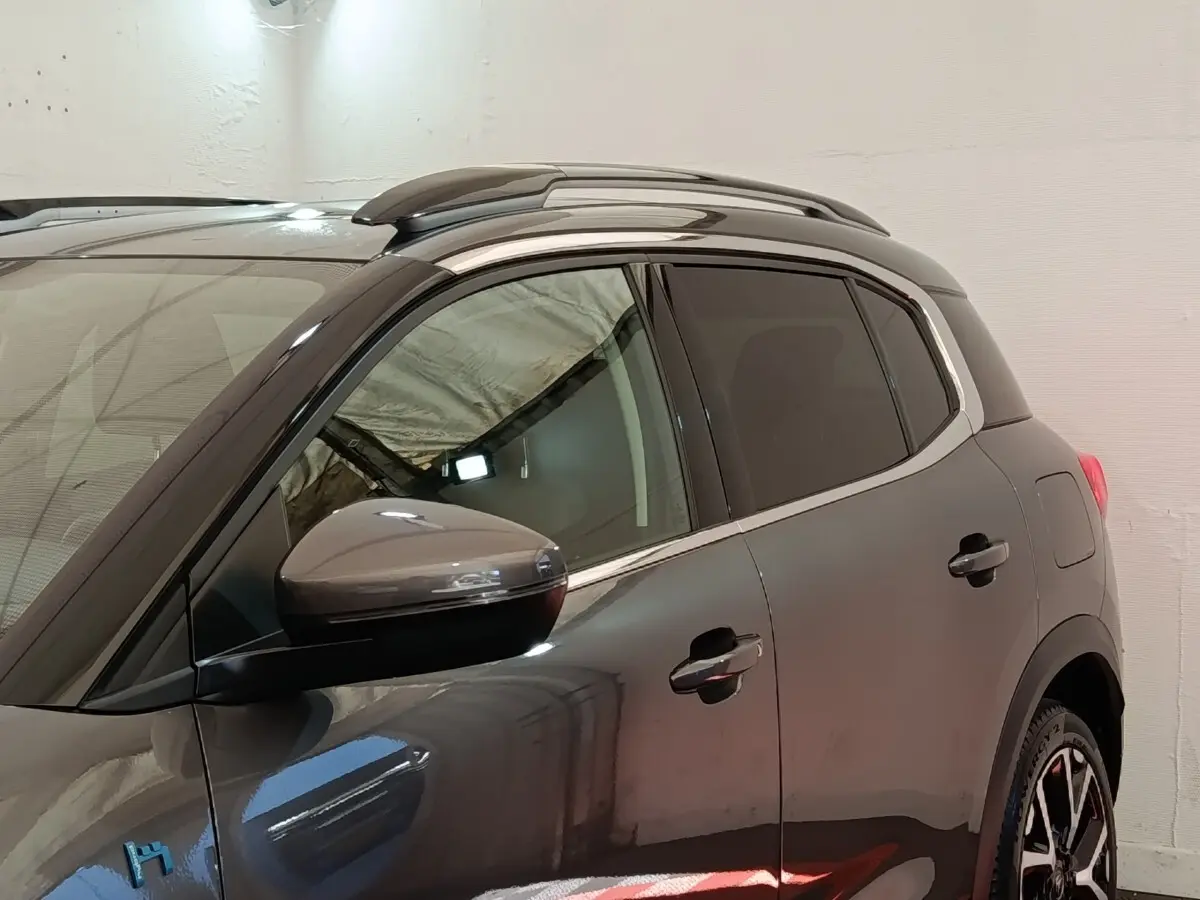 Vue de profil côté gauche d'un Citroën C5 Aircross Hybrid gris foncé avec barres de toit chromées et vitres teintées.