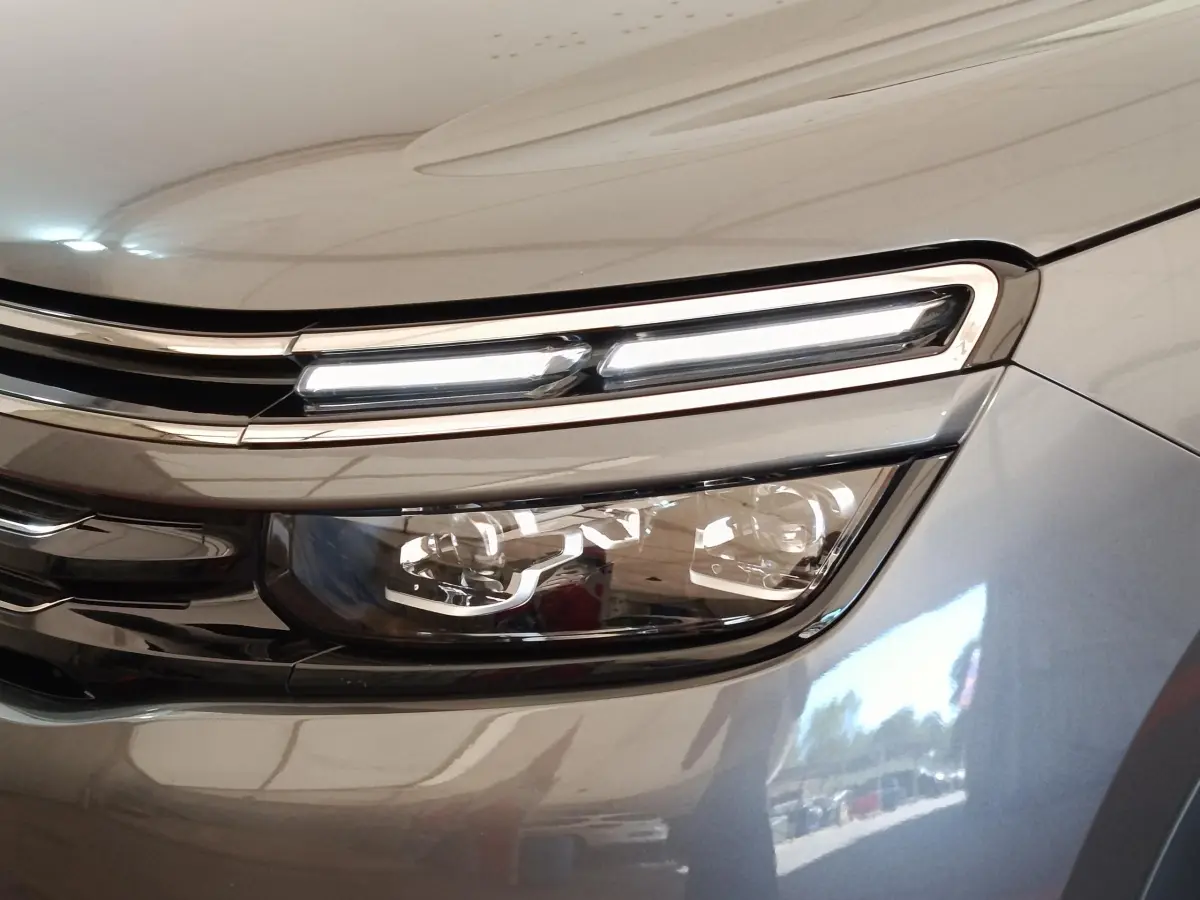 Gros plan sur le phare avant droit du Citroën C5 Aircross Hybrid gris foncé avec éclairage LED allumé.