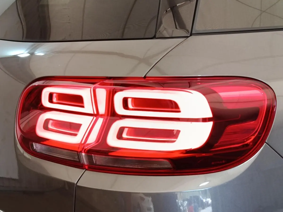 Gros plan sur le feu arrière droit rouge et blanc d’un Citroën C5 Aircross Hybrid gris foncé, vue latérale.