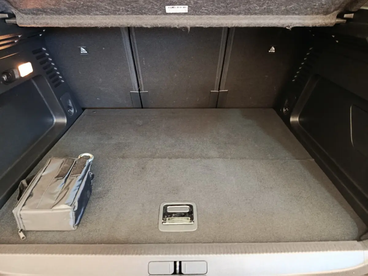 Coffre spacieux vu de face, intérieur gris foncé avec rangement noir et éclairage latéral allumé.