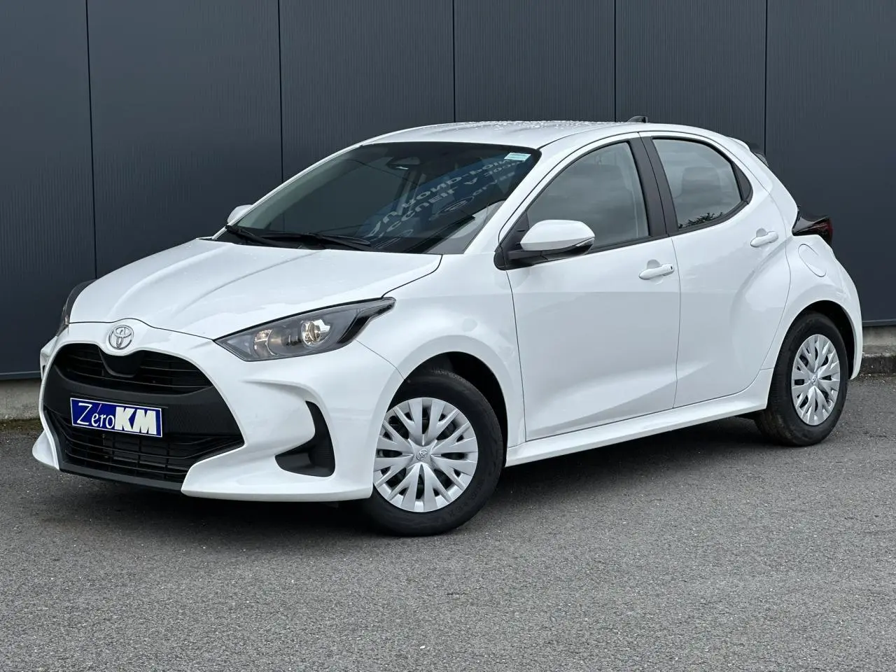 Toyota Yaris hybride blanc pur vue 3/4 avant droit avec calandre noire et jantes tôles.