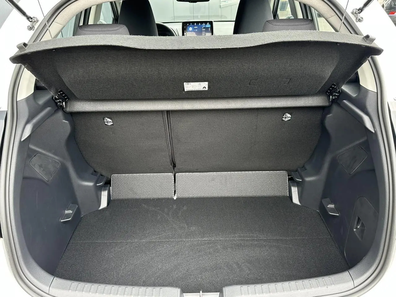 Coffre ouvert vu de l'arrière d'une Toyota Yaris blanche, montrant le double plancher et la banquette arrière noire.
