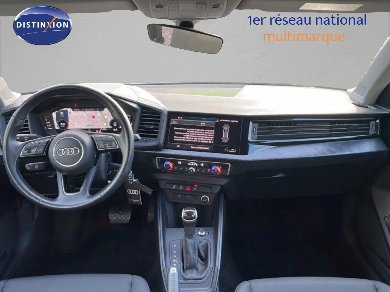 Intérieur de l'Audi A1 Sportback 2023 en blanc glacier, vue du tableau de bord avec volant et écran central tactile.