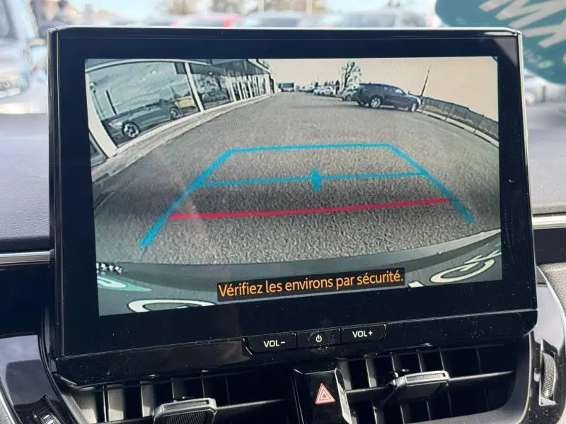 Vue écran caméra de recul affichant l'arrière d'une Toyota Corolla noire avec lignes de guidage bleues et rouges.
