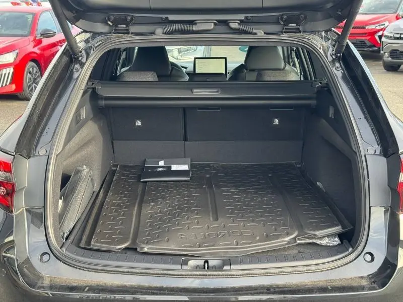 Vue arrière ouverte du coffre noir de la Toyota Corolla 2025, avec tapis de coffre et tablette tactile visible à l'avant.