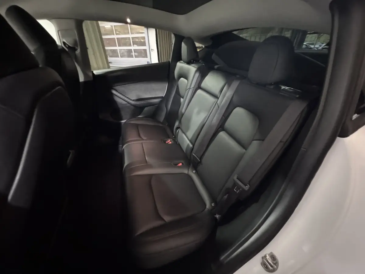 Vue intérieure côté droit des sièges arrière en cuir noir du Tesla Model Y blanc, version Grand Autonomie Dual Motor AWD.