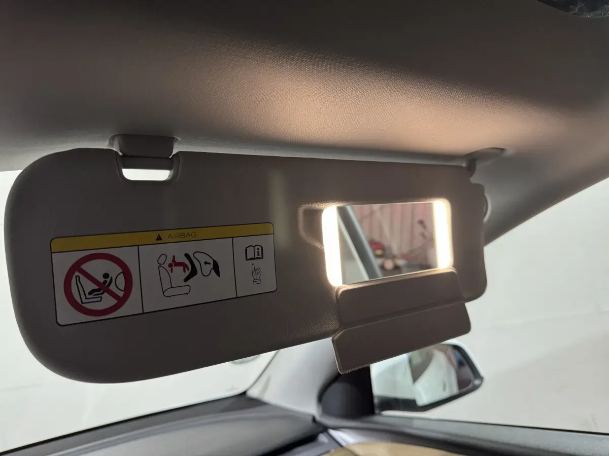 Détail du pare-soleil côté conducteur avec miroir éclairé dans l’habitacle blanc d’un Tesla Model Y 2022.