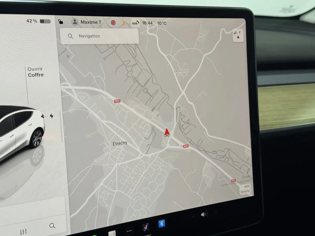 Écran tactile central affichant la navigation et l’image d’une Tesla Model Y blanche vue de côté gauche, intérieur moderne.