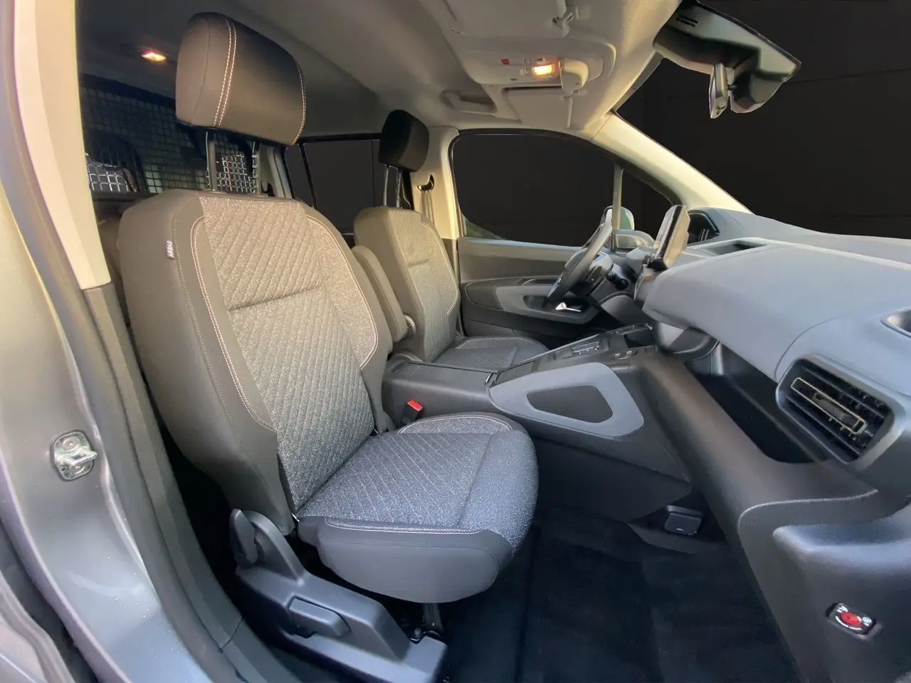 Vue intérieure côté droit du Peugeot Rifter gris acier 2026, montrant les sièges avant et le tableau de bord.