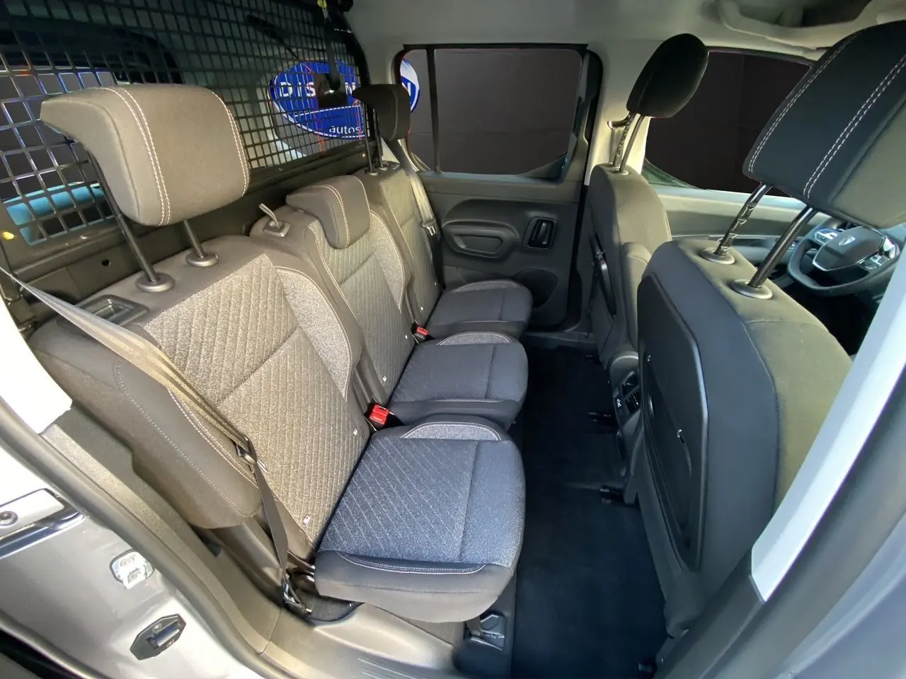 Vue intérieure côté gauche du Peugeot Rifter gris acier 2026, montrant les trois sièges arrière et la cloison de séparation.