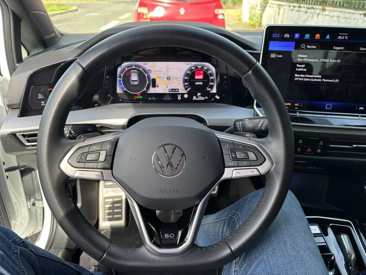 Vue intérieure centrée sur le volant noir de la Volkswagen Golf blanche 2024, avec tableau de bord numérique et logo Edition 50 visible.