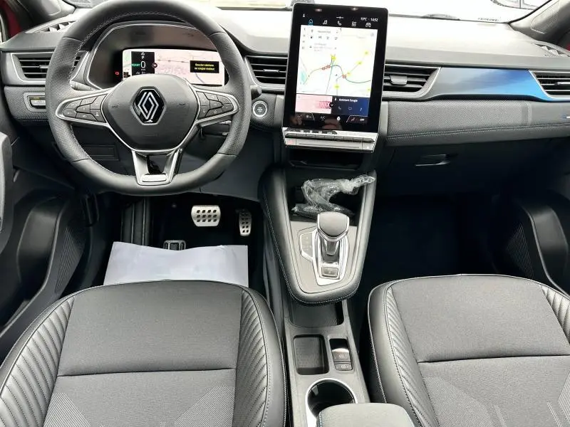 Vue intérieure avant du Renault Captur 2025 avec tableau de bord noir, écran tactile vertical et volant multifonction.