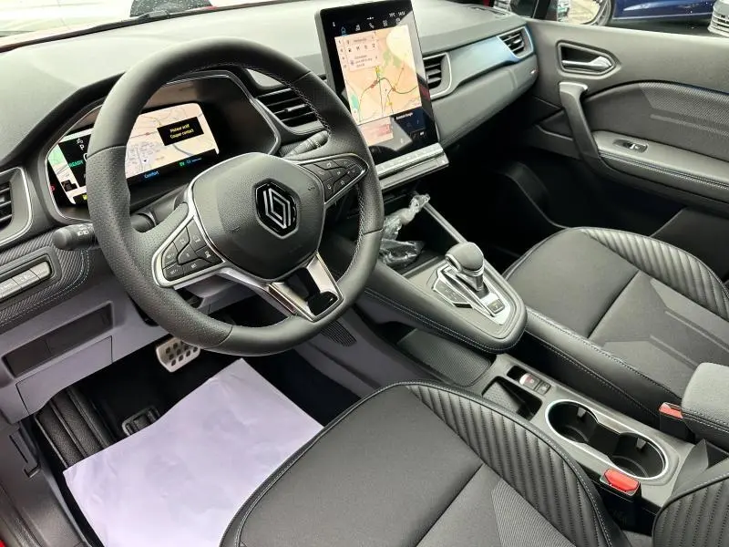 Vue intérieure côté conducteur du Renault Captur 2025, tableau de bord noir avec écran tactile vertical et volant multifonction.
