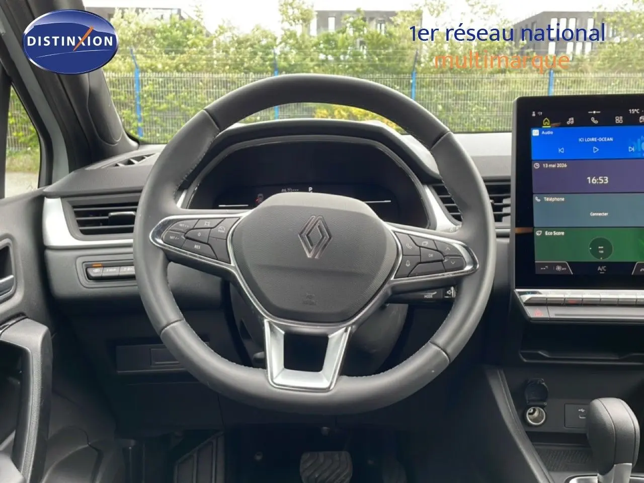 Vue intérieure centrée sur le volant cuir et l’écran tactile du tableau de bord de la Renault Symbioz gris Rafale Métal.