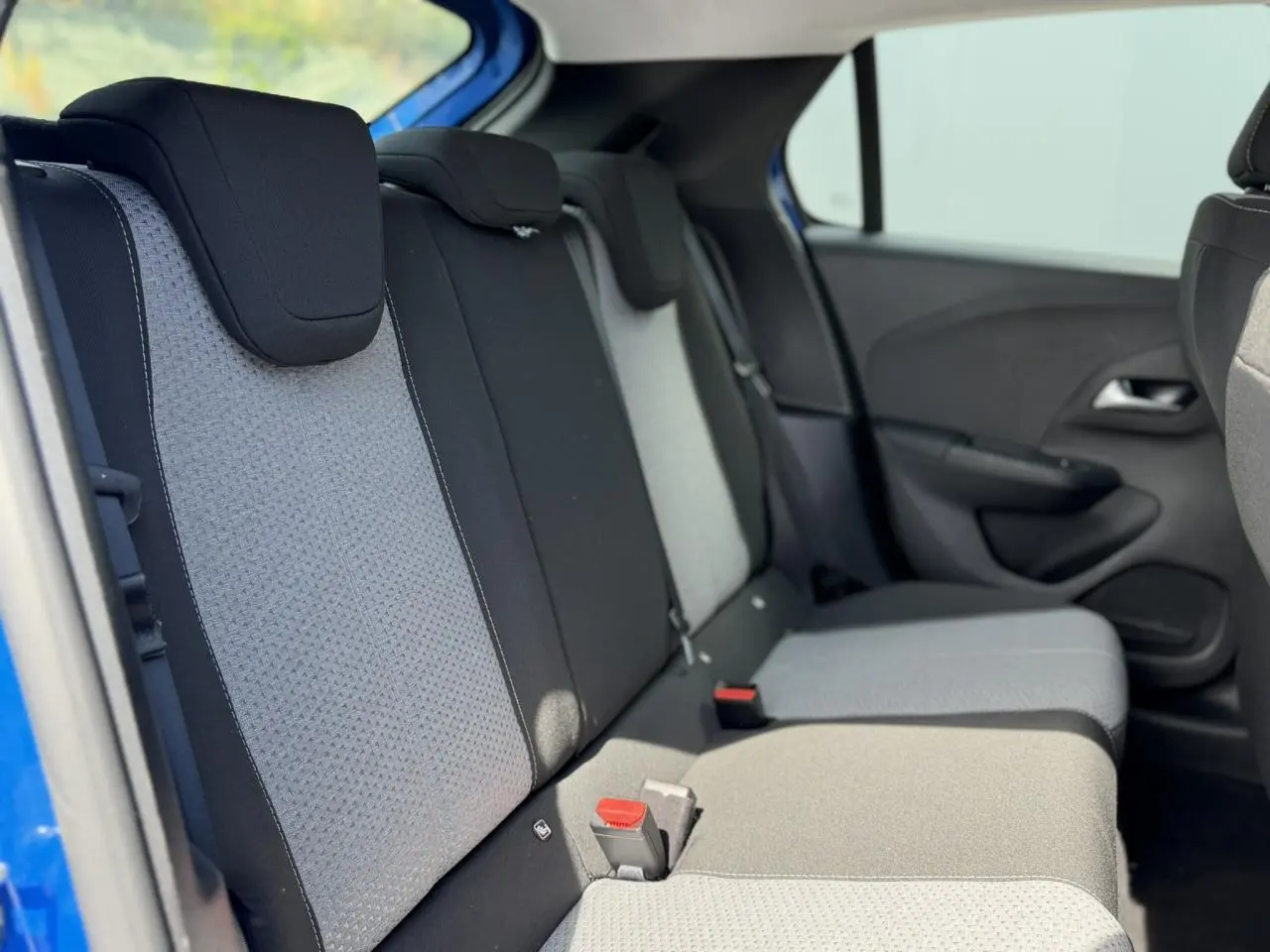 Vue latérale intérieure des sièges arrière de la Opel Corsa 2025 bleu Voltaic avec tissu bicolore gris et noir.