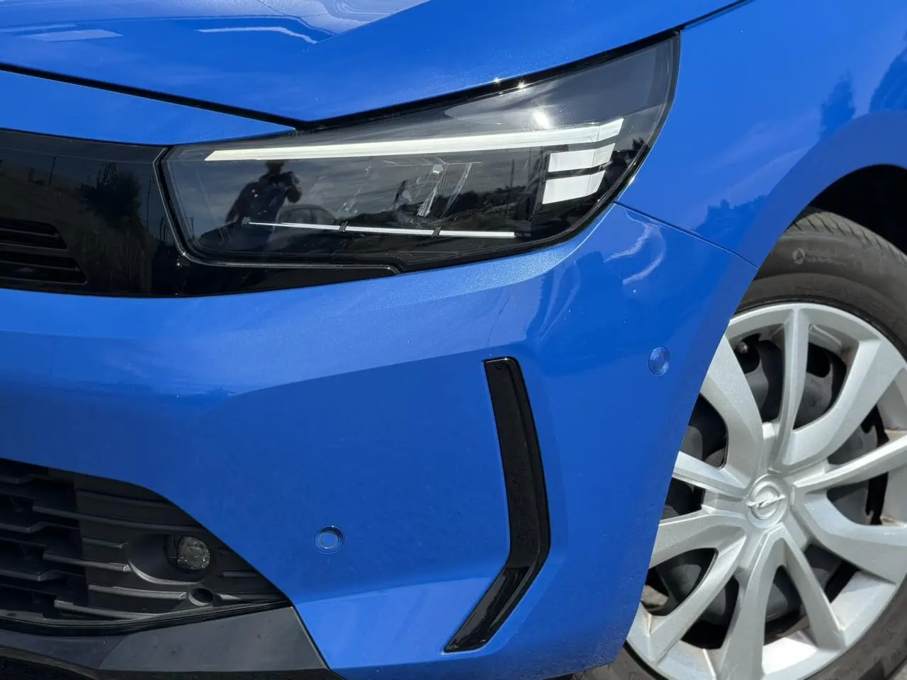 Gros plan sur l'avant droit bleu Voltaic de l'Opel Corsa 2025, mettant en valeur le phare LED et la jante alliage.