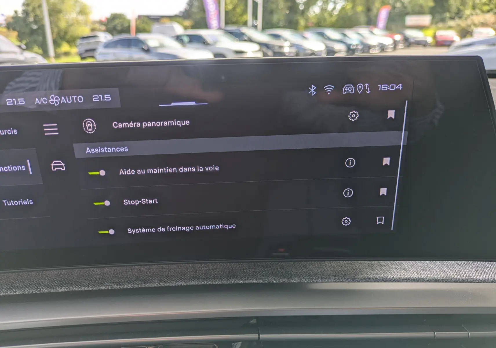 Écran tactile intérieur du Peugeot 3008 Hybrid 145 GT affichant les assistances à la conduite, avec tableau de bord et reflet extérieur.