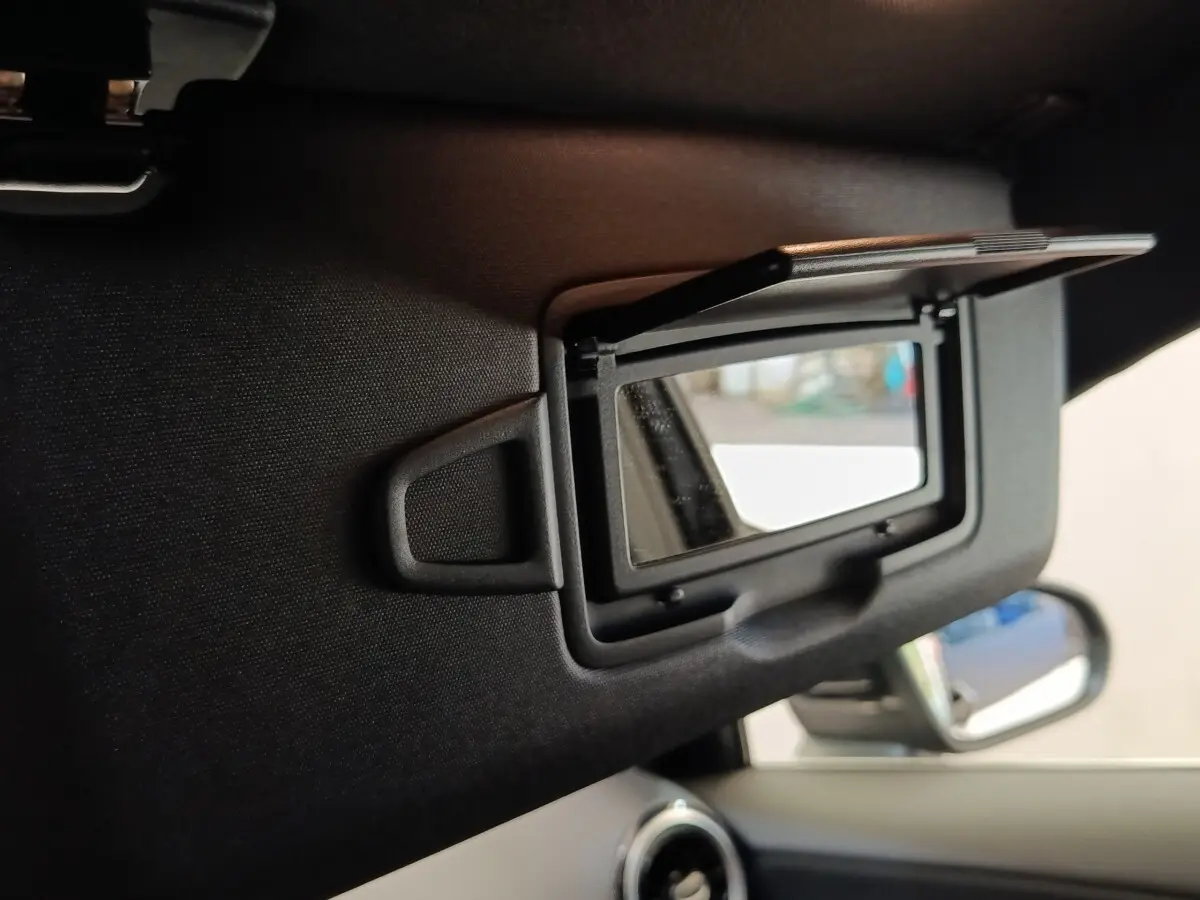 Détail du miroir de courtoisie ouvert sur le pare-soleil côté conducteur d’une Mercedes Classe A noire, intérieur visible.