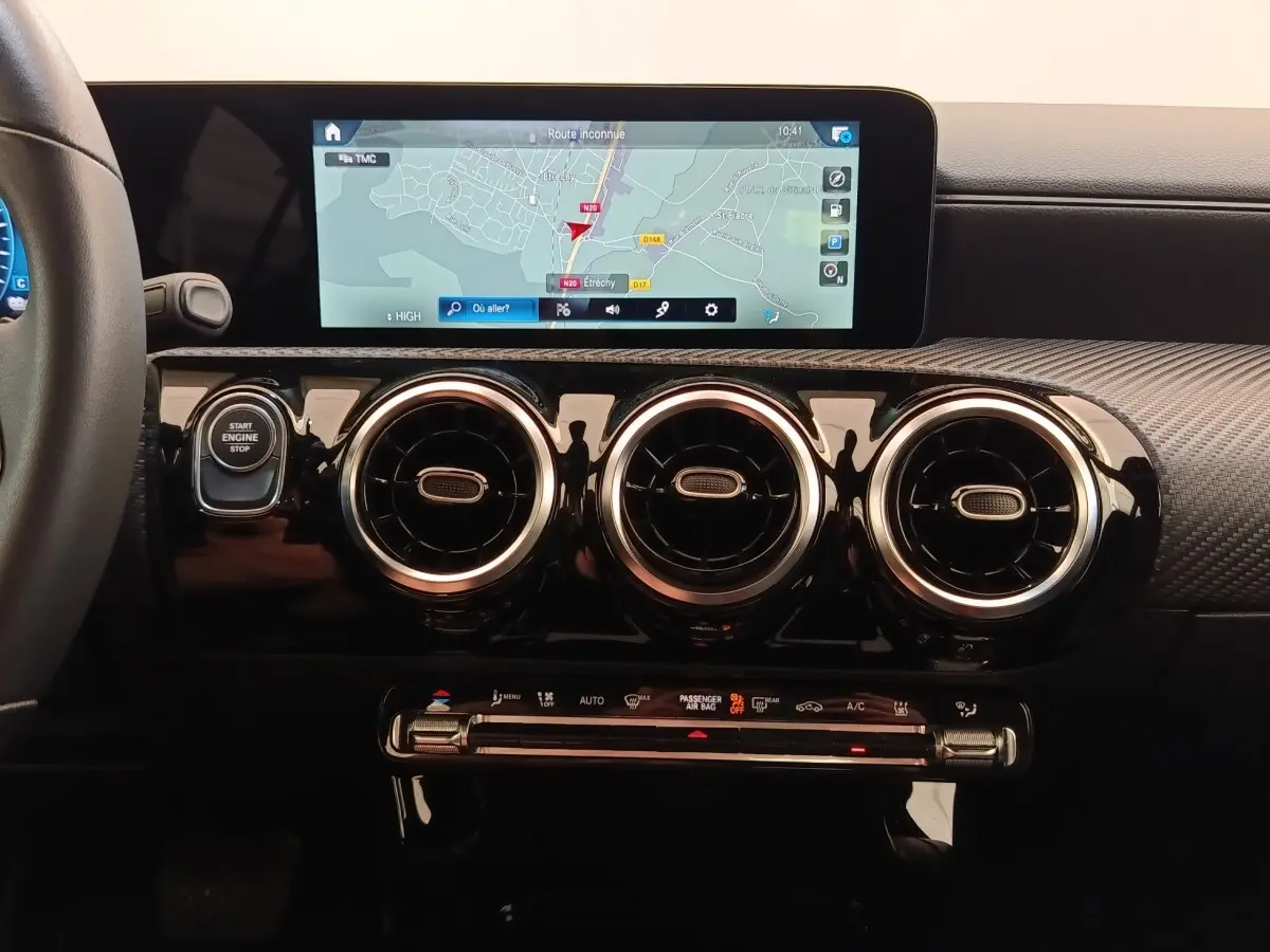 Vue rapprochée du tableau de bord noir de la Mercedes Classe A 250 e avec écran tactile de navigation et aérateurs ronds chromés.