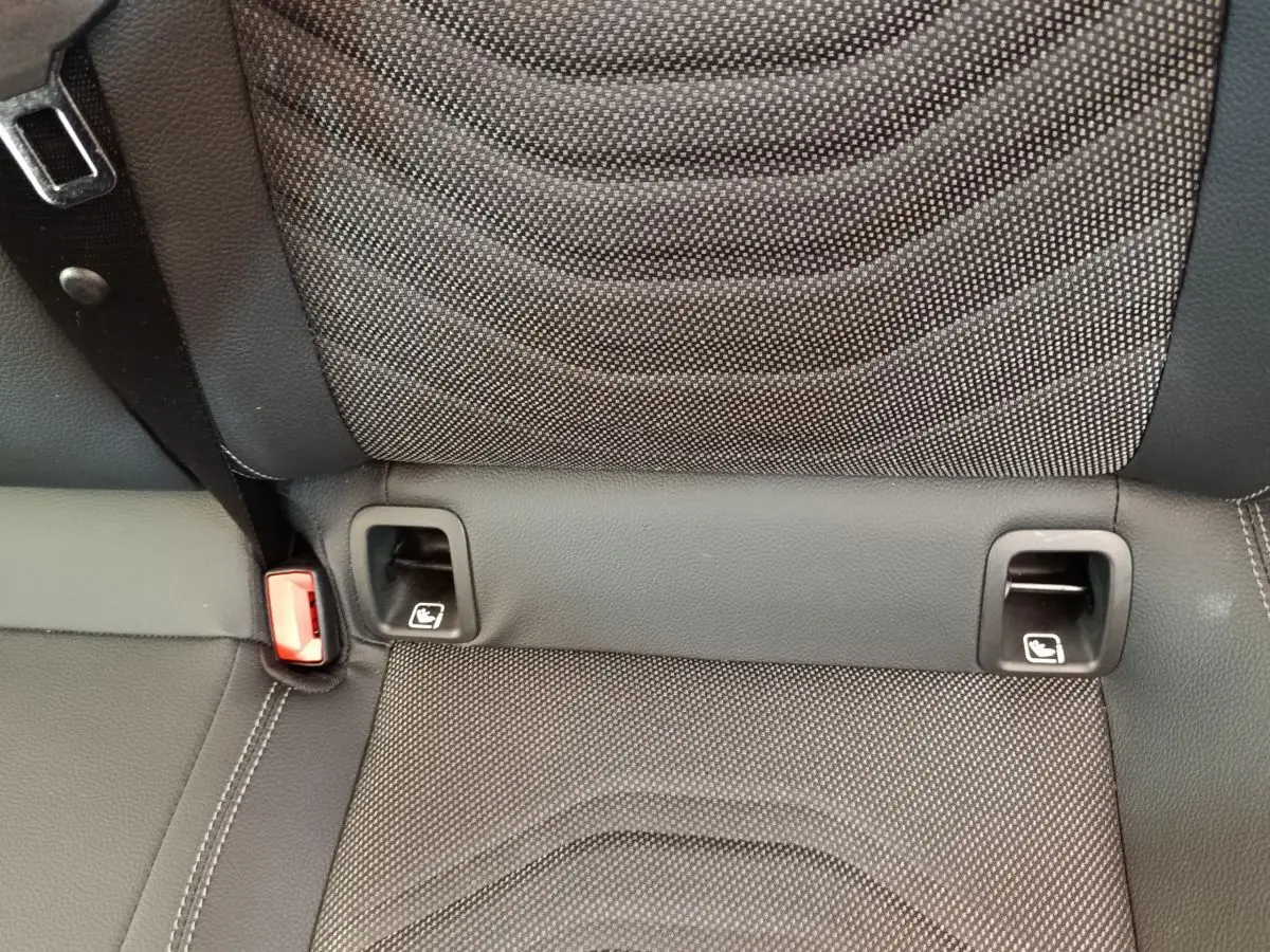 Gros plan sur la banquette arrière noire de la Mercedes Classe A avec fixation Isofix et ceinture rouge visible.