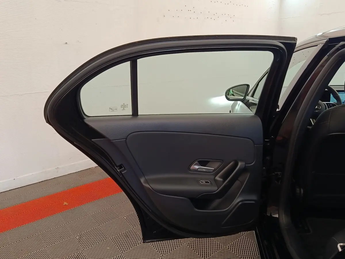 Vue intérieure de la porte arrière gauche ouverte d’une Mercedes Classe A 250 e Business Line noire, avec garniture noire.