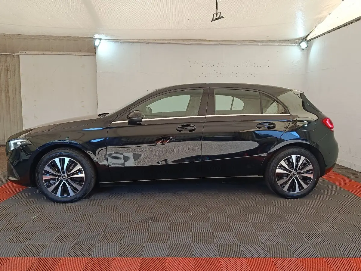 Profil latéral gauche d'une Mercedes Classe A 250 e Business Line noire, avec jantes alliage et poignées de porte intégrées.