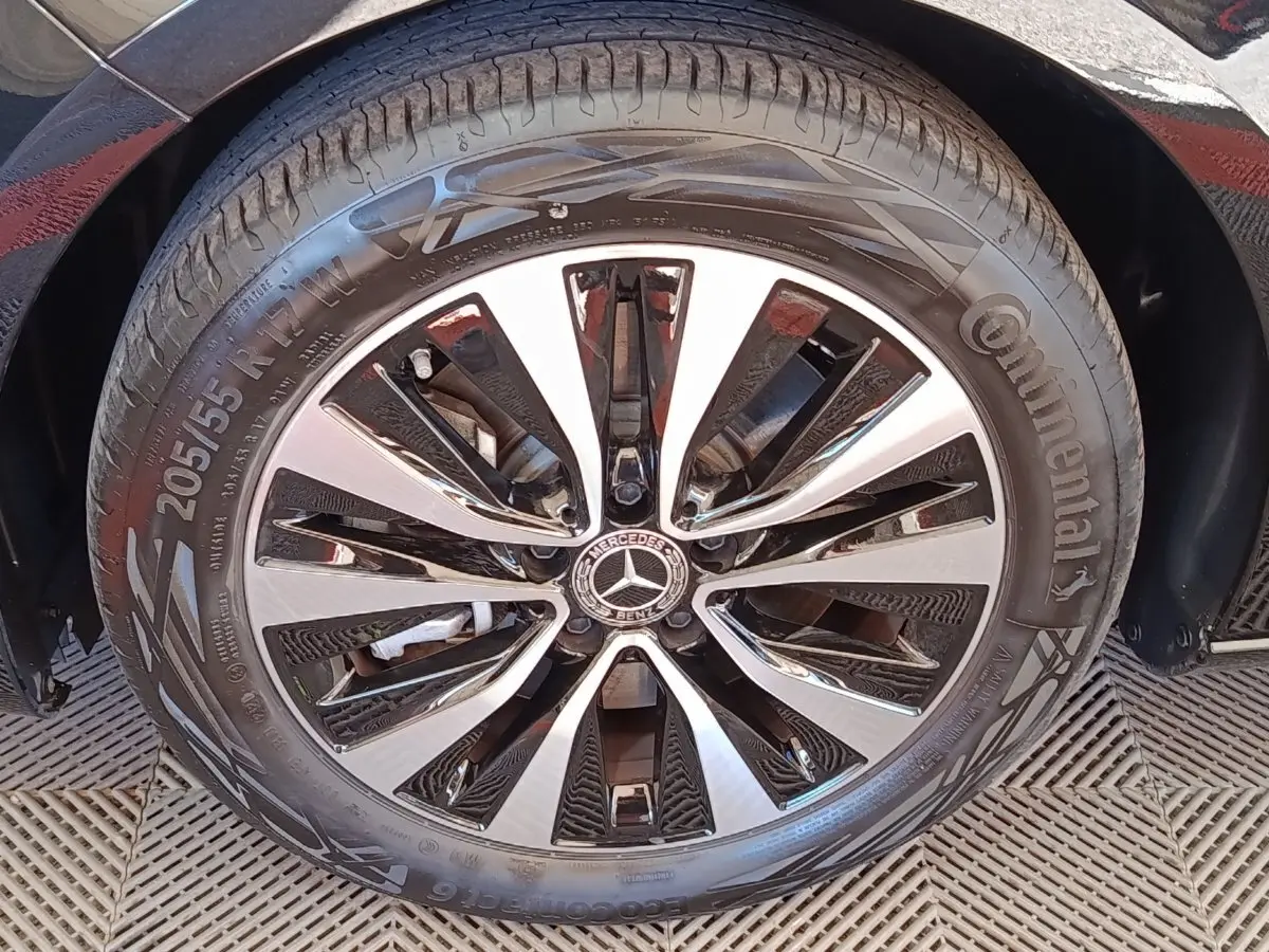 Gros plan sur la roue avant droite d’une Mercedes Classe A noire, mettant en valeur la jante alliage bicolore et le logo central.