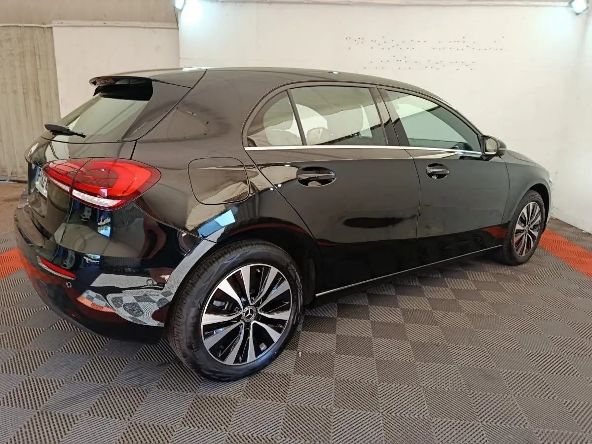 Vue 3/4 arrière droite d'une Mercedes Classe A 250 e Business Line noire avec jantes alliage et spoiler de toit.