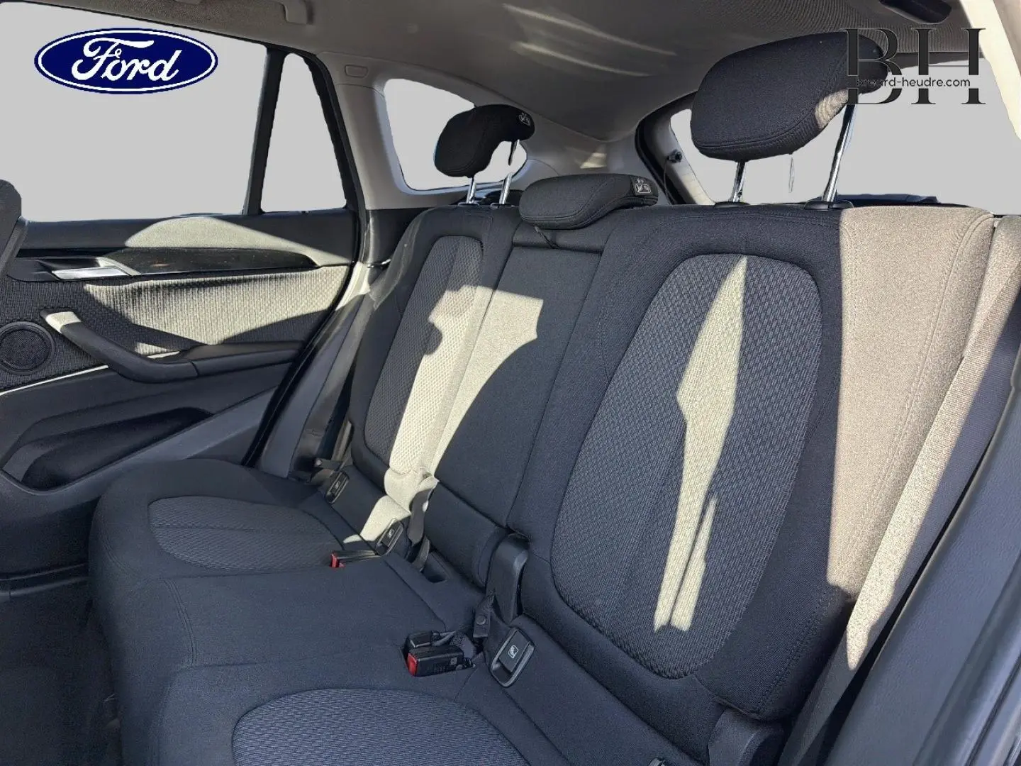 Vue intérieure arrière montrant la banquette tissu noire et les appuie-têtes d'un BMW X1 sDrive18dA 2018.