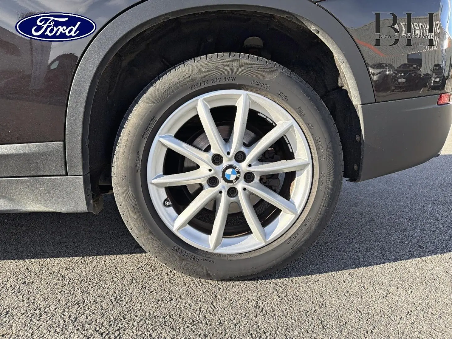 Gros plan sur la roue arrière droite d’un BMW X1 sDrive18dA 2018 noir Saphirschwarz avec jante alu argentée.