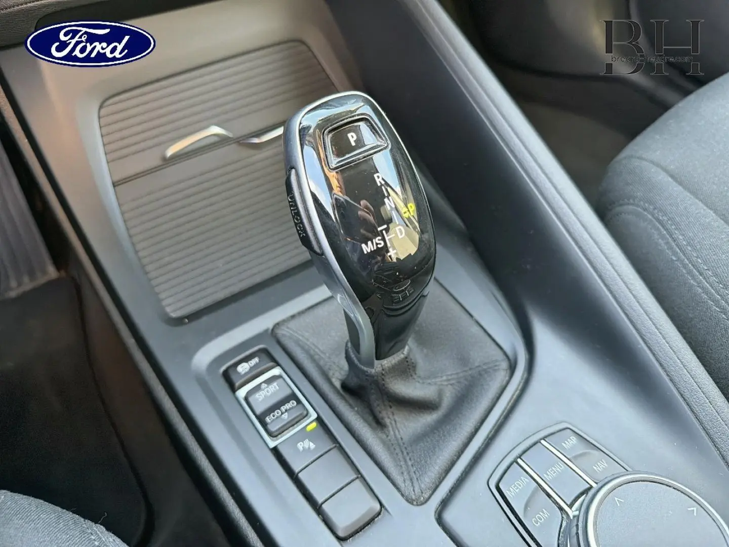 Le levier de vitesses automatique noir vu en gros plan dans l'habitacle d'une voiture, entouré de boutons de contrôle.